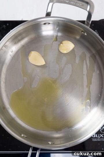 Sauteing whole crushed garlic in  a pan.
