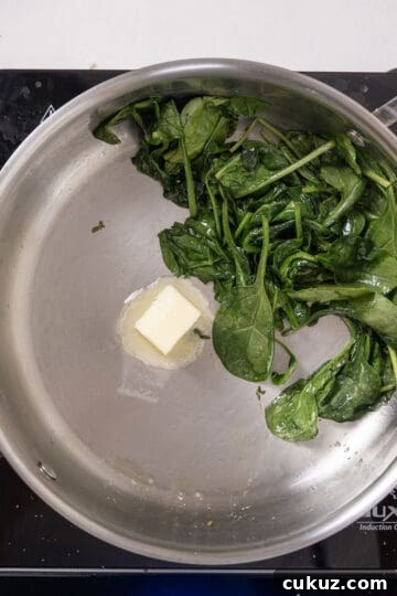 Butter added to spinach in a pan.