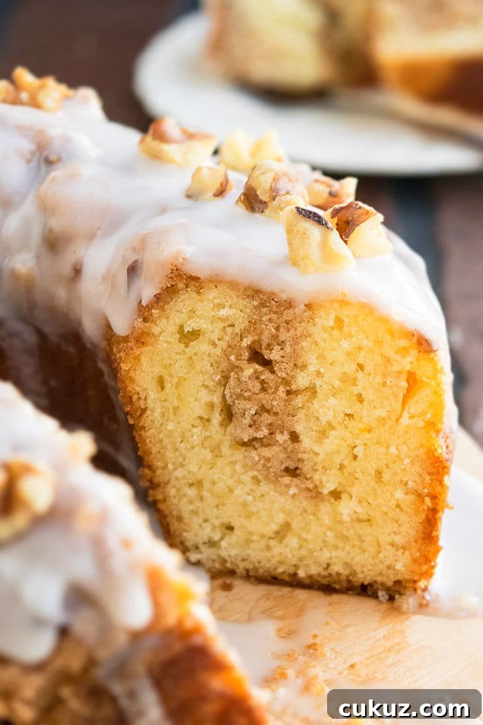 Sliced Bundt Cake With Cinnamon Pecan Streusel Filling and Vanilla Glaze on Rustic Wood Board- Closeup Shot