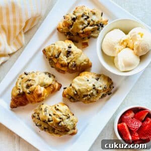 crookie croissant stuffed with cookie on a plate with a bowl of ice cream.
