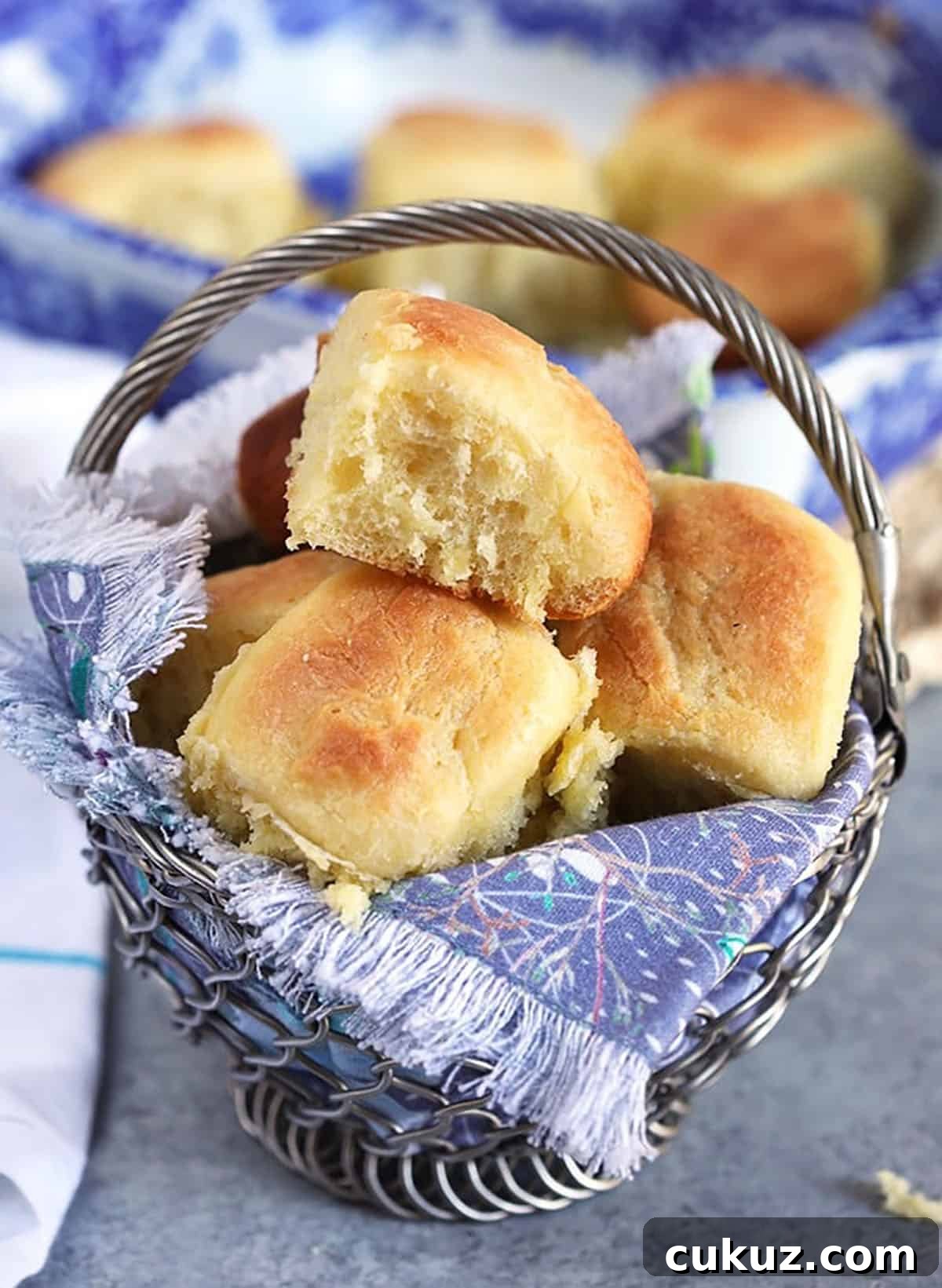 Dinner rolls in a basket with blue linens.