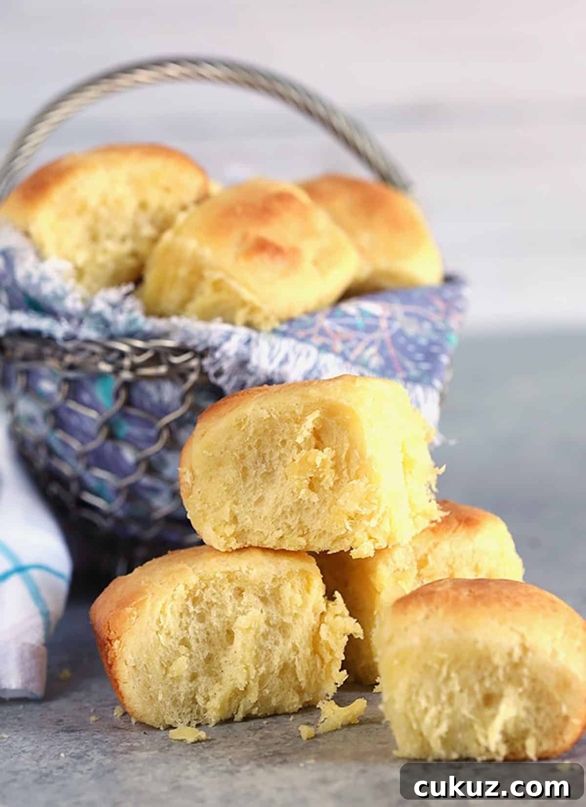 Brioche buns stacked on a gray surface with a metal basket in the background.