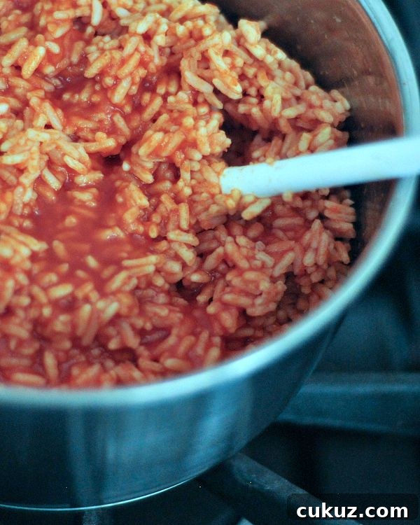 Spanish rice cooking in a saucepan on the stove