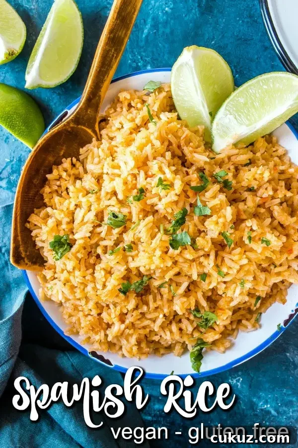 overhead view of serving bowl of Spanish Rice garnished with cilantro and lime wedges