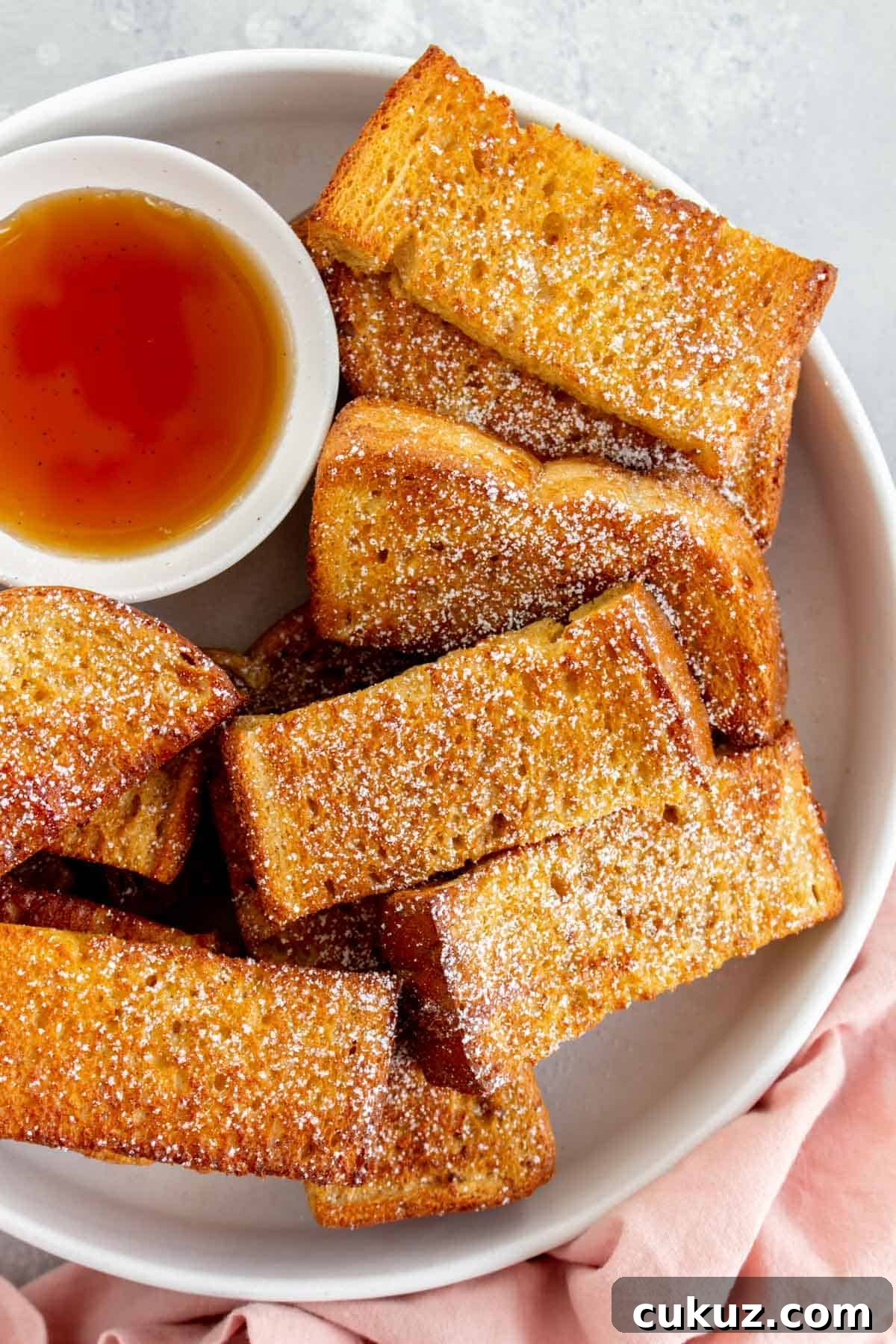 Close up of air fryer french toast sticks with powdered sugar dusted on top.