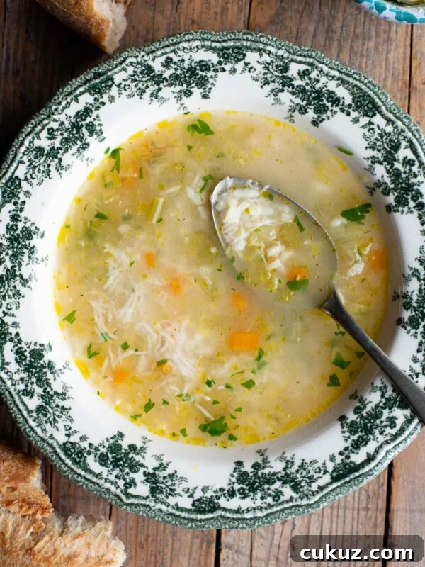 An overhead shot of an Italian rice soup in a green and white bowl with a spoon inside.