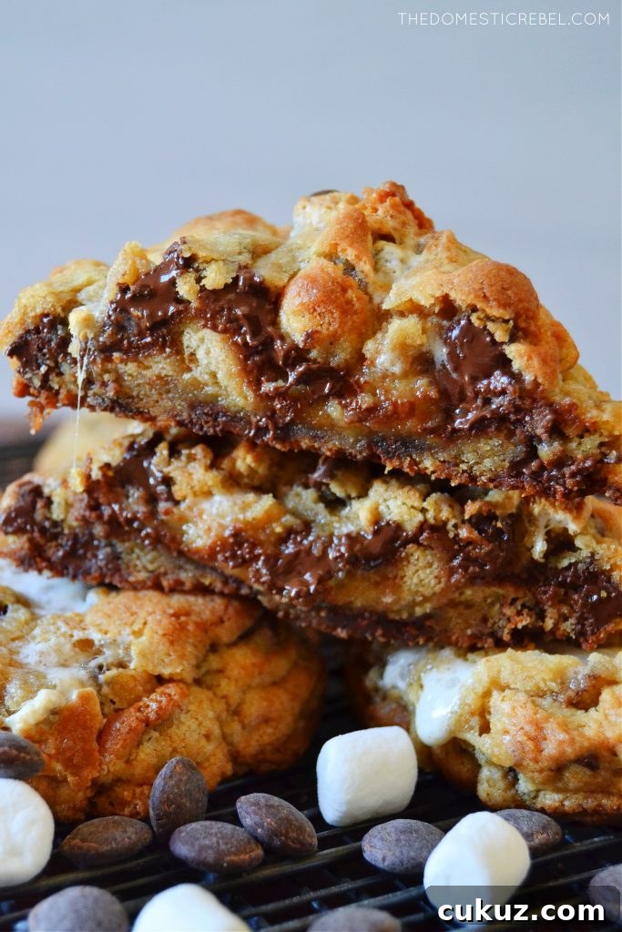 a cut open gooey s'mores cookie stacked with marshmallows and chocolate chips
