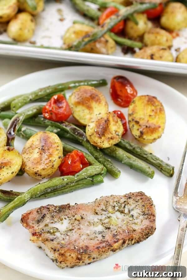 Italian Pork Chop Sheet Pan Dinner on a white plate with a fork.