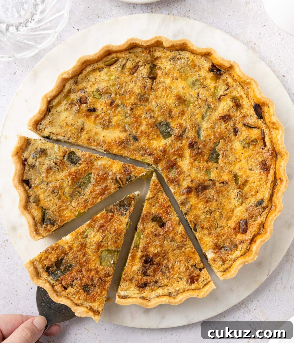 Picking up a slice of quiche with a cake server - seen from above.