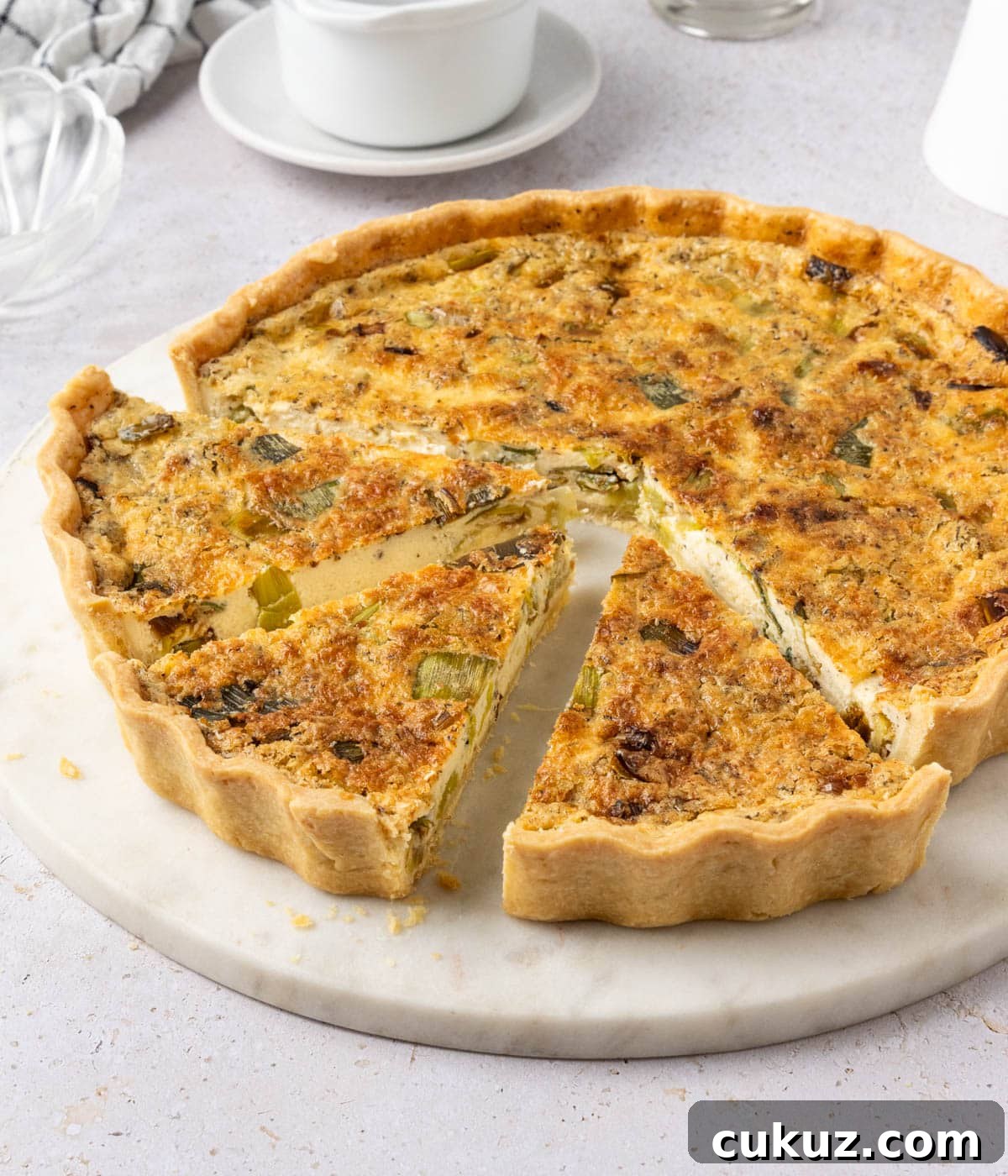 45 degrees angle view on the quiche with three slices cut out.