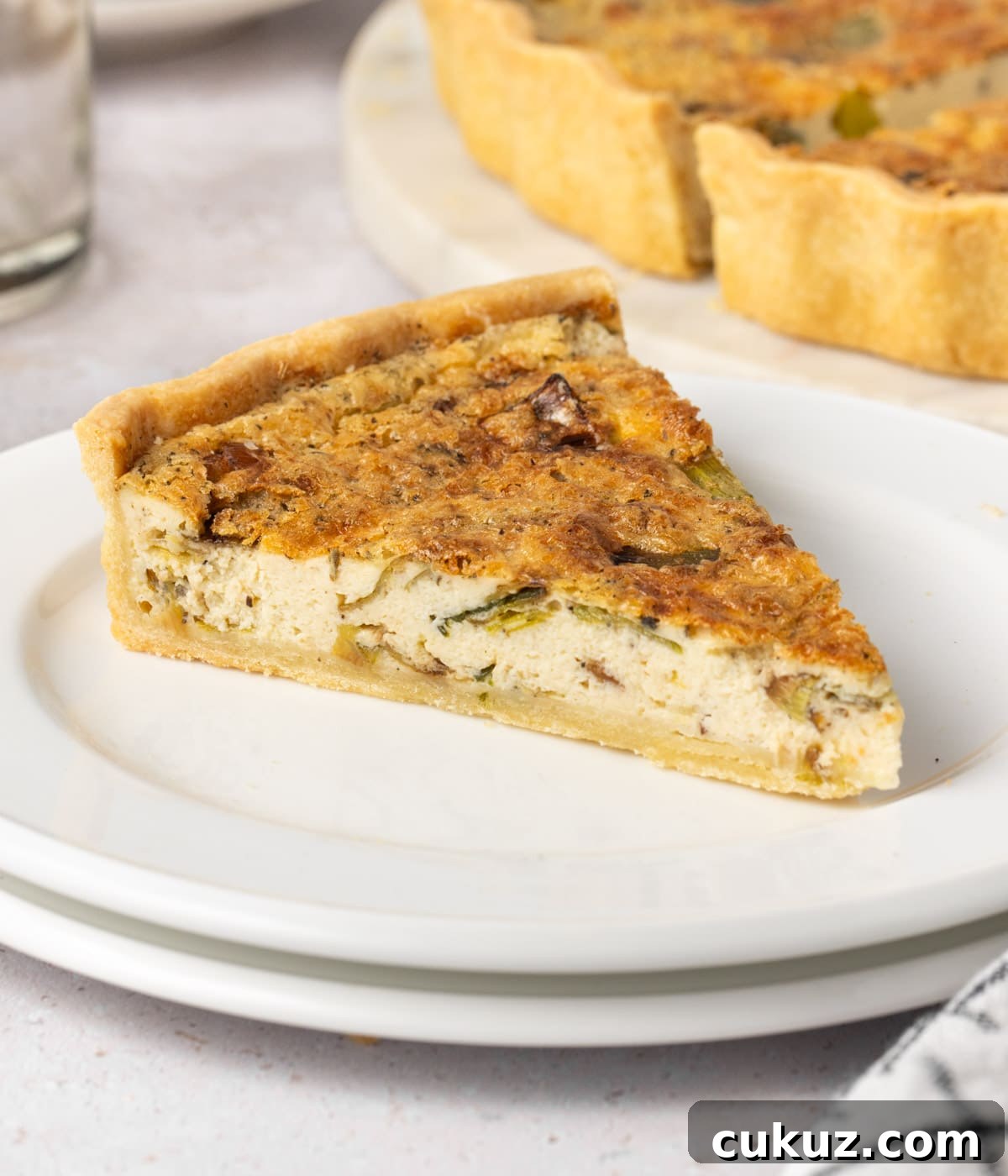 One slice of quiche on a small white plate.