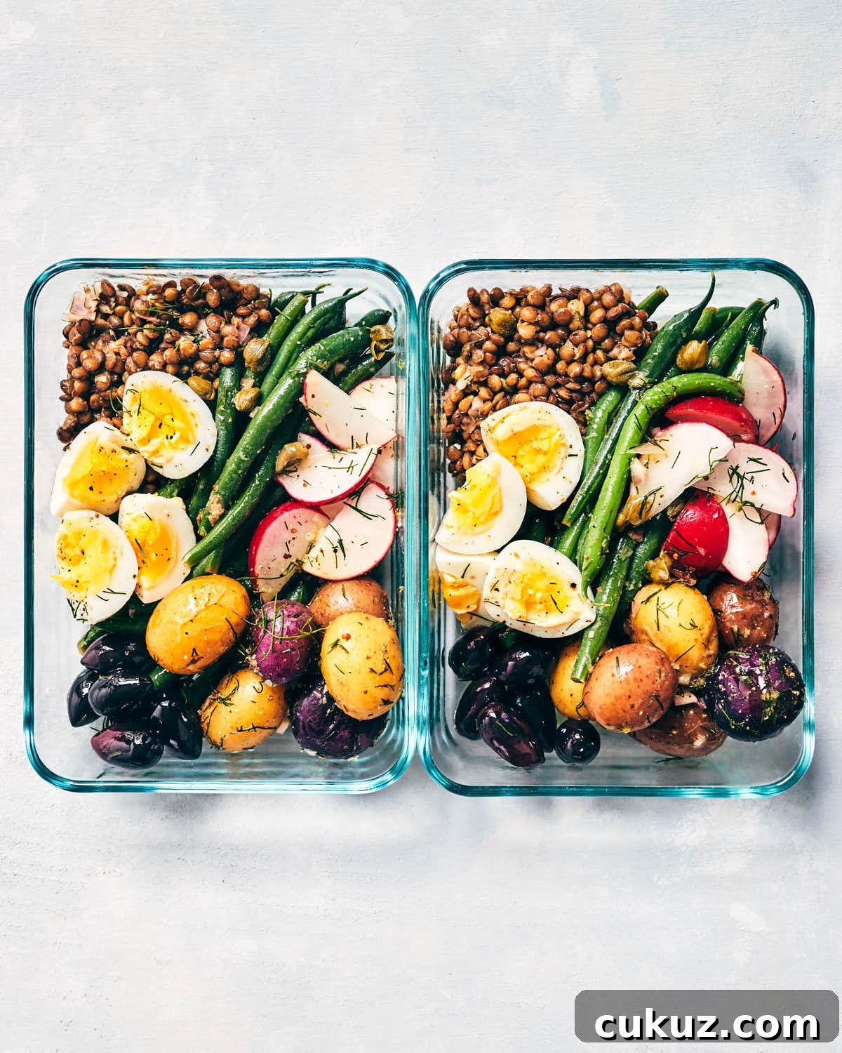 Two pyrex containers of nicoise salad ready to packed away for a meal prepped lunch
