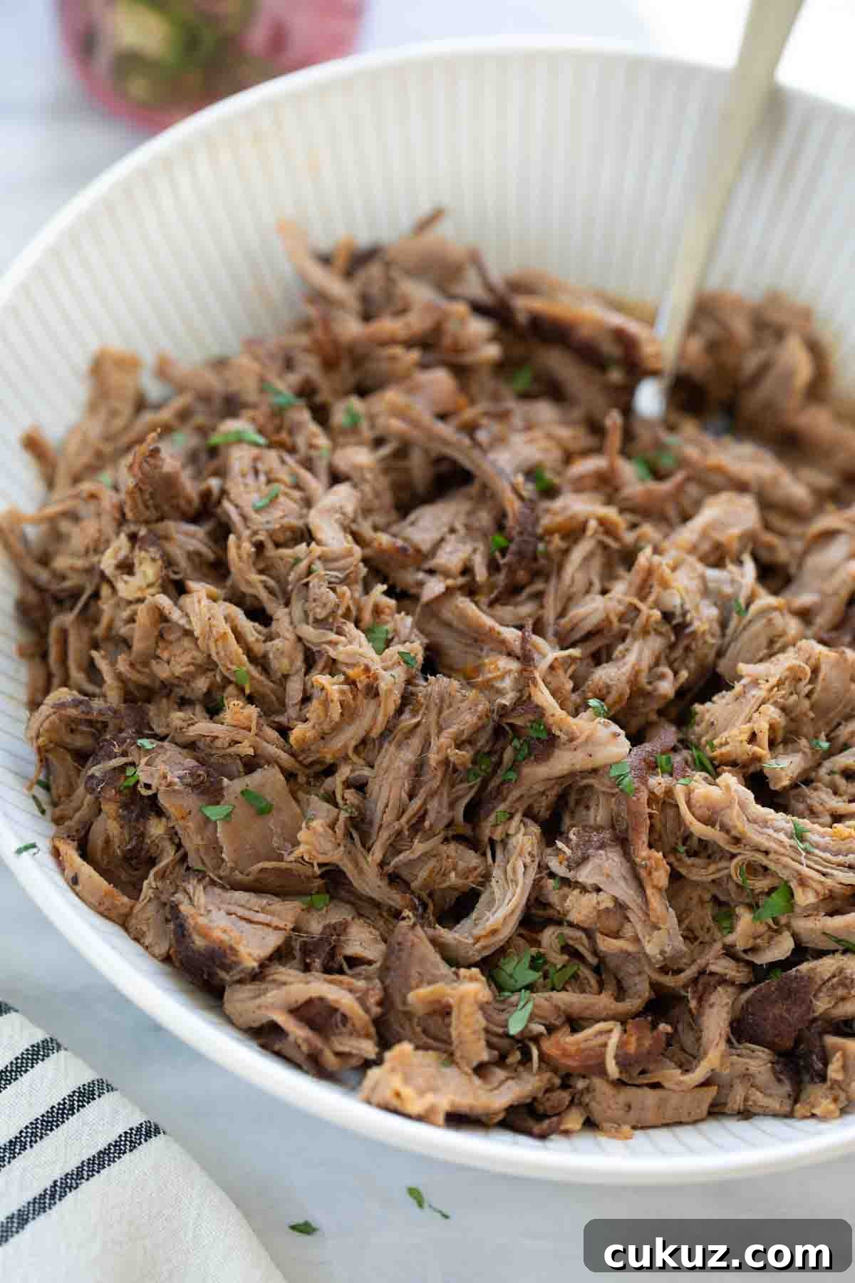 Slow-Cooker Sweet Pork Tacos Recipe for Flavorful Weeknight Meals 8 shredded pork tenderloin in white bowl topped with cilantro on marble background