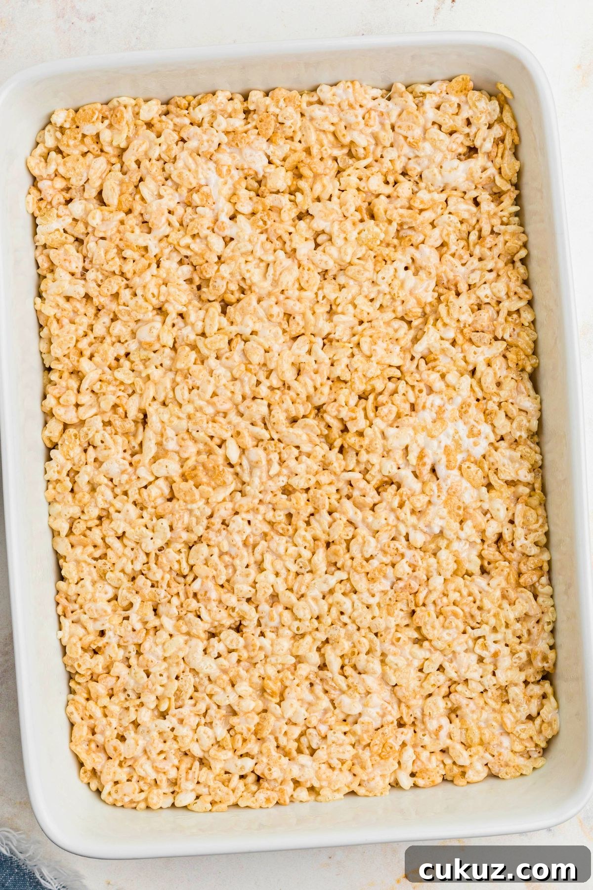 Rice krispie treats in a white casserole dish, pressed down. 