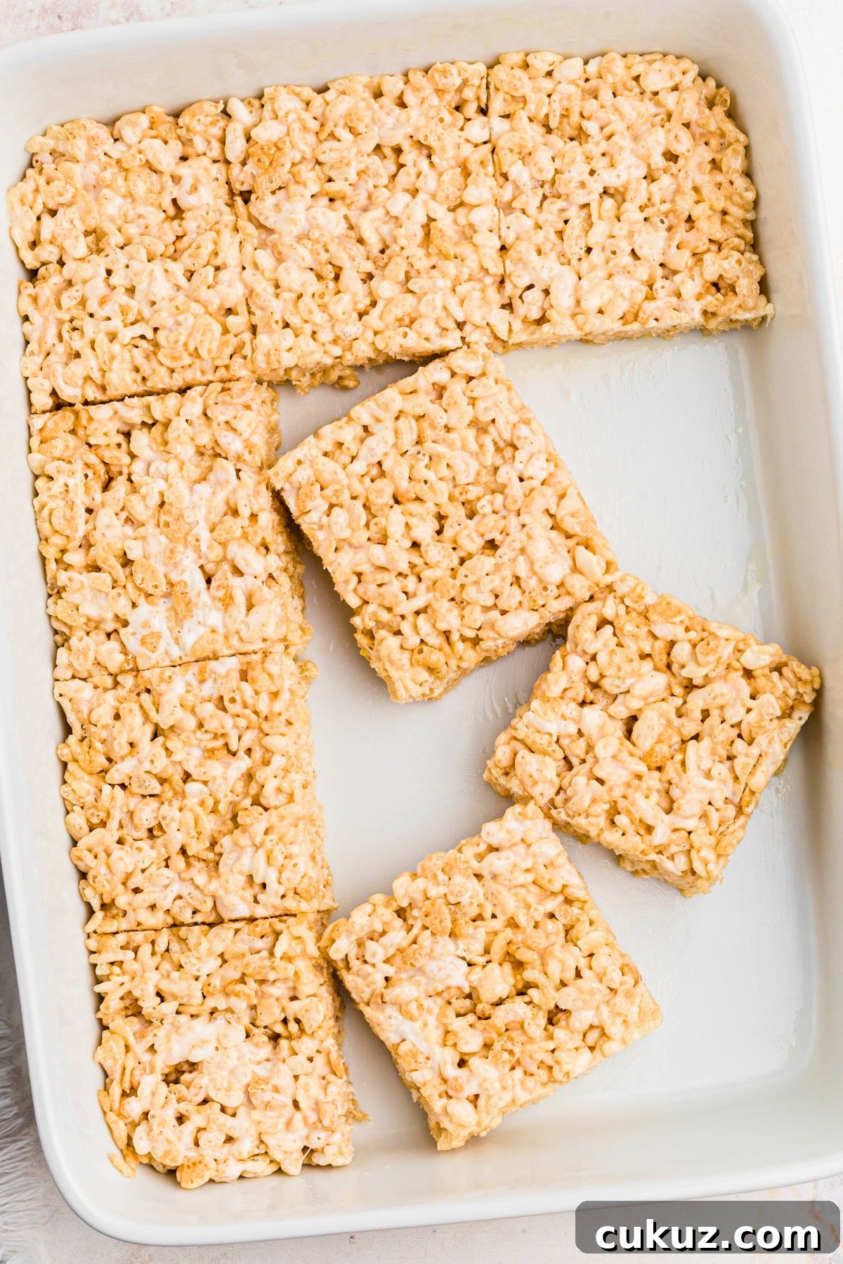 Rice krispie treats cut into squares in a white 9x13 dish. 