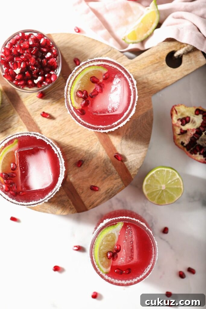 Three pomegranate margaritas from above on marble and wood