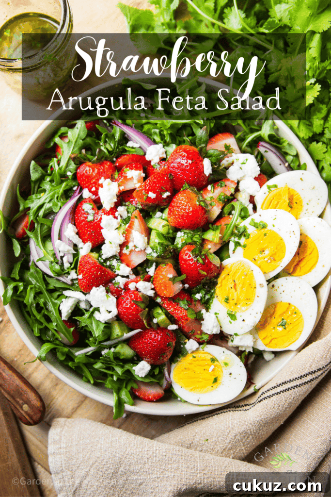 Salad in a bowl with strawberry, arugula, feta, red onions and hard boiled eggs.