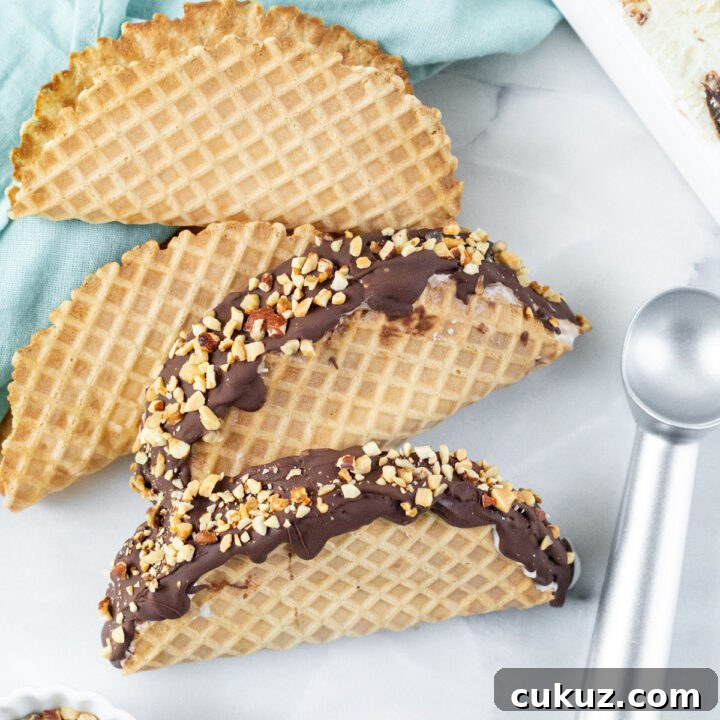 two choco tacos next to waffle shells chopped nuts and an ice cream scoop
