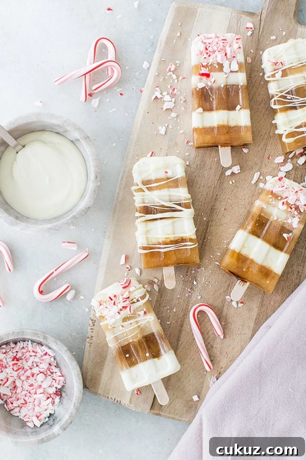 Peppermint Cold Brew Popsicles Recipe: Refreshing Iced Coffee Treat 2 Striped popsicles with coffee and white chocolate with peppermint candy cane crushed over the top