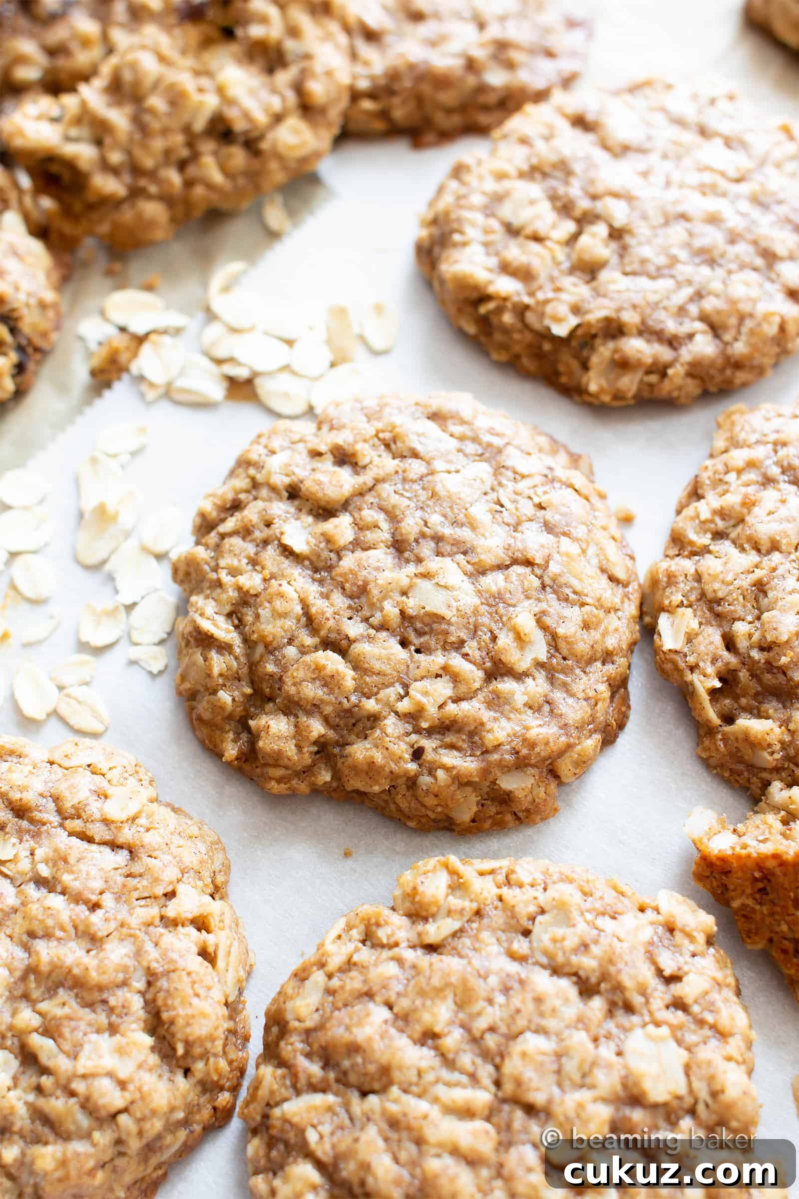 close up of vegan oatmeal cookies on parchment paper with rolled oats