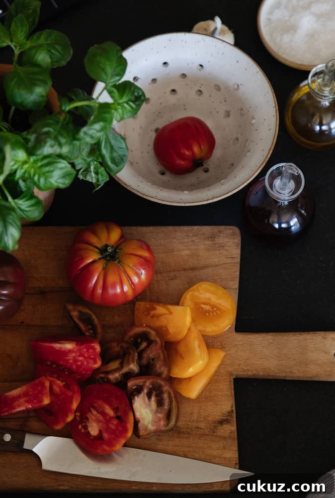 Rustic Panzanella Salad with Heirloom Tomatoes and Basil 6 top view of heirloom tomatoes being sliced on a rustic wood cutting board with a colander and basil plant