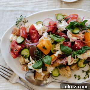 Rustic Panzanella Salad with Heirloom Tomatoes and Basil 7 fork and spoon laying on a white platter filled with panzanella salad