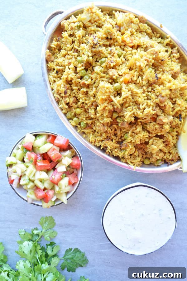 A large silver platter of yellow rice and a tomato and cucumber salad