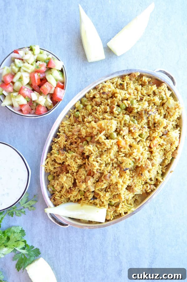 A plate of yellow vegetable biryani with kachumber salad
