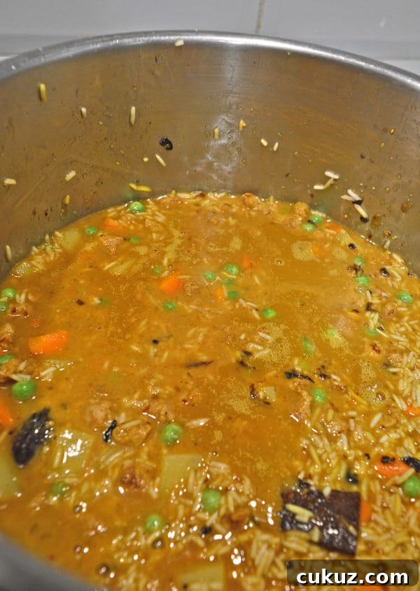 A pot with rice vegetables and a brown liquid in it