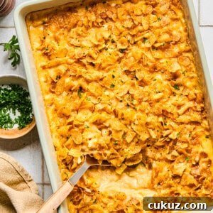 cheesy hashbrown casserole in a dish with a spoon taking a scoop