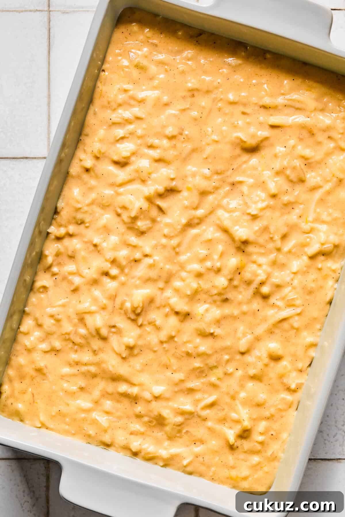 Cheesy hashbrown casserole mixture in a baking dish.