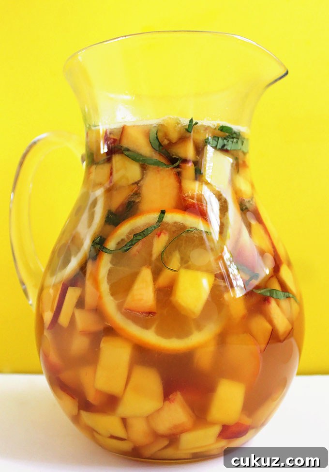Peach Mango Sangria. SO easy to make. Refreshing, delicious. It's like summertime in a glass! #sangria #summercocktail #recipe | robustrecipes.com