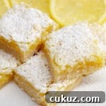 Close up image of lemon bars from scratch on white boards with sliced lemons.