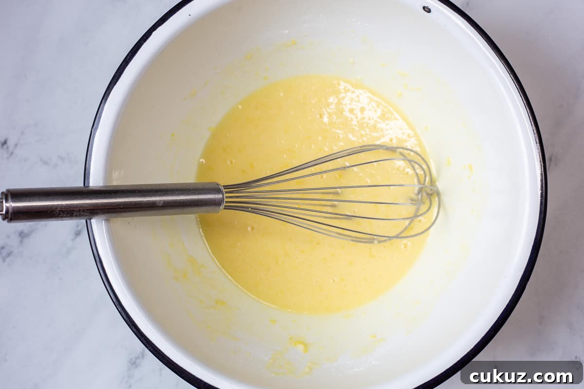 Lemon curd ingredients in mixing bowl with whisk.