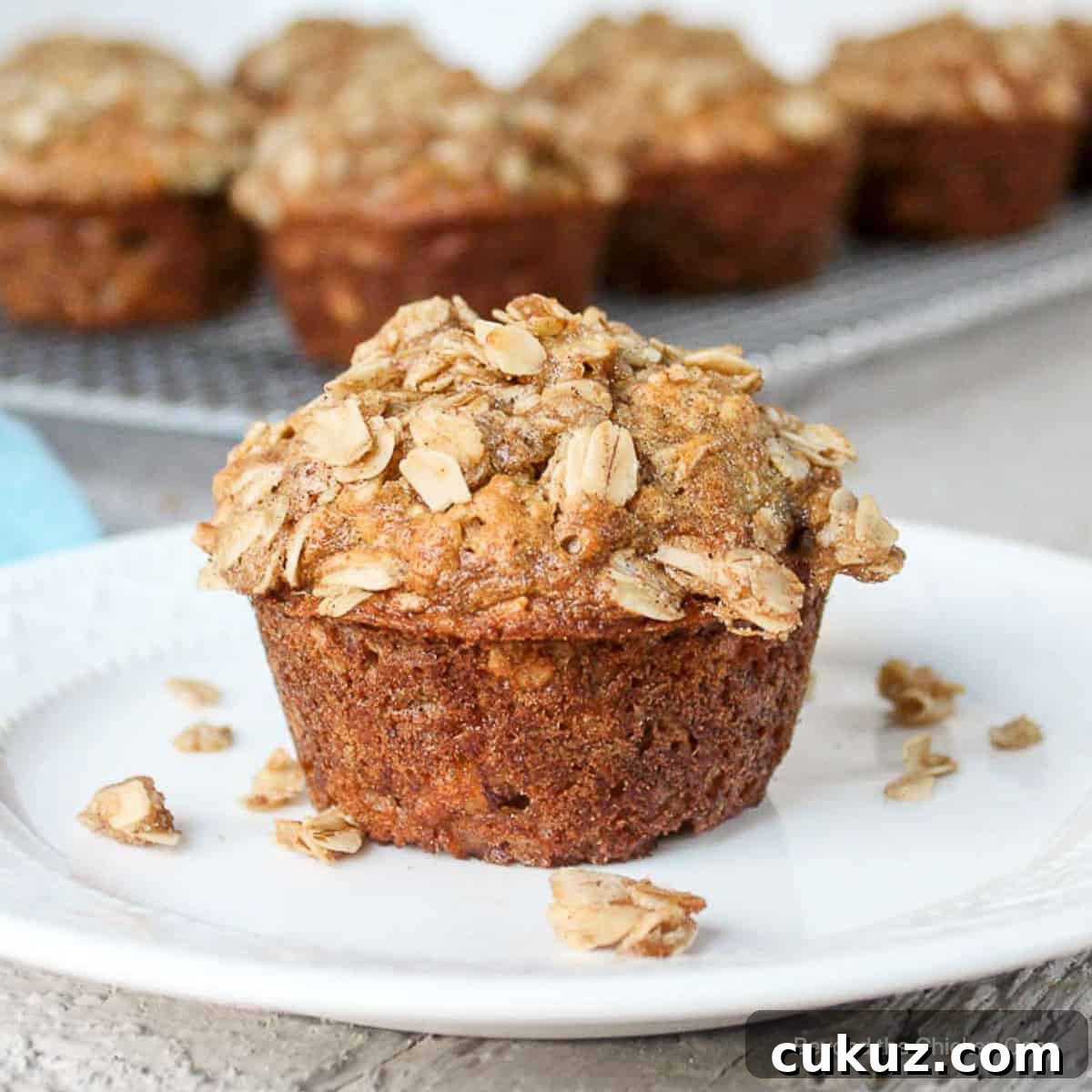 A single oatmeal banana muffin topped with a crumbly topping on a plate.