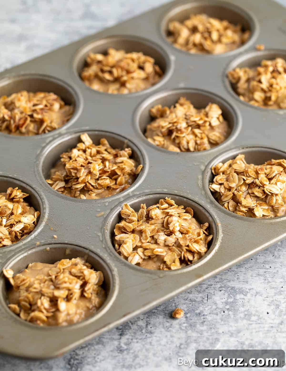 Unbaked oat muffins in a muffin tin. 