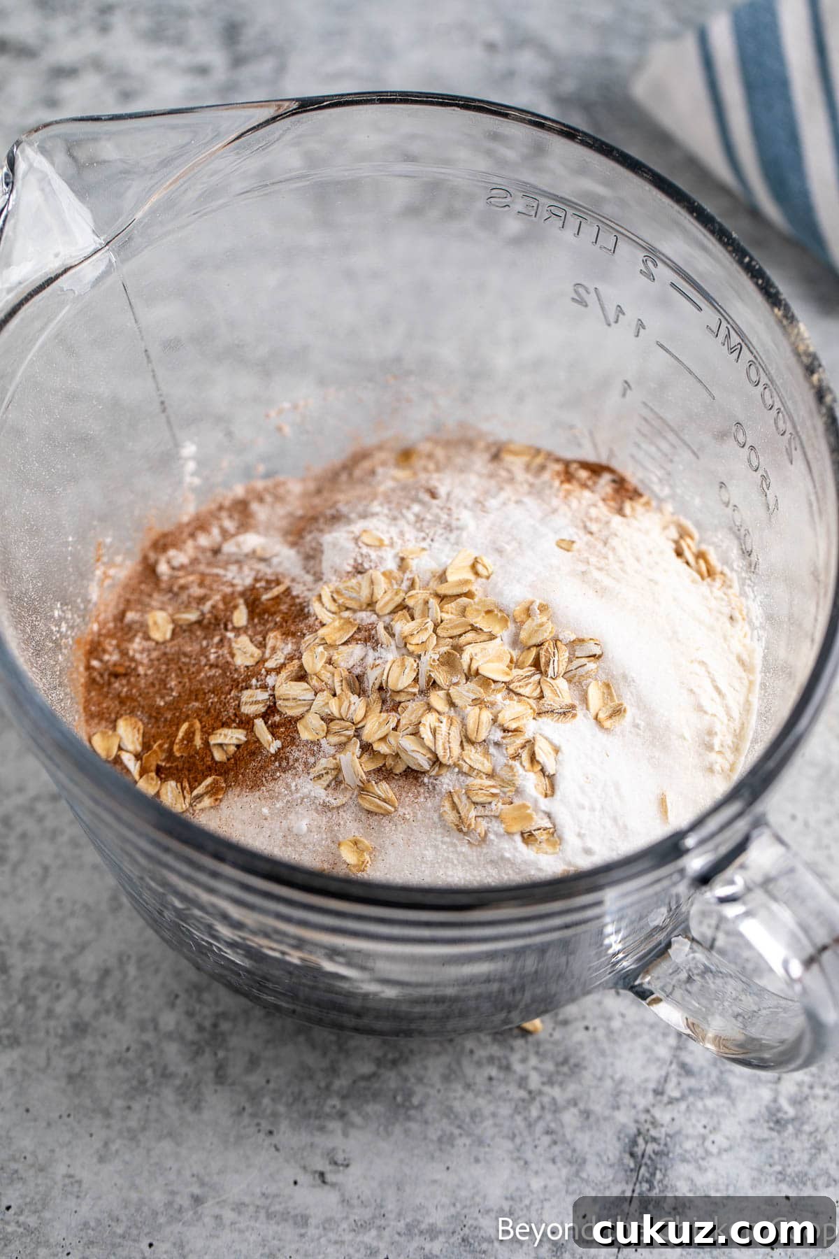 Mixing flour, oats, sugar and spices together in a glass bowl. 