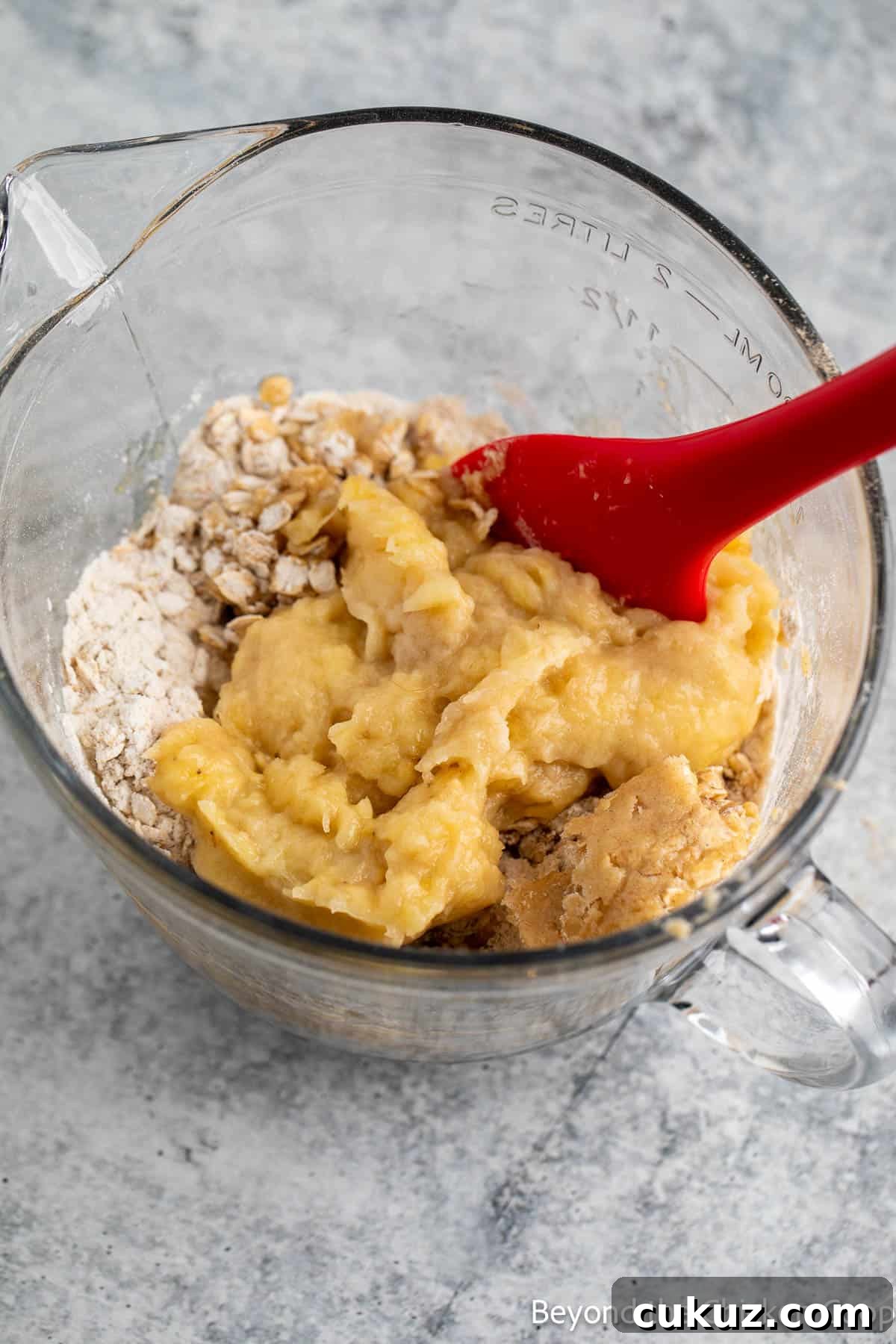 Mashed bananas being stirred into muffin batter. 