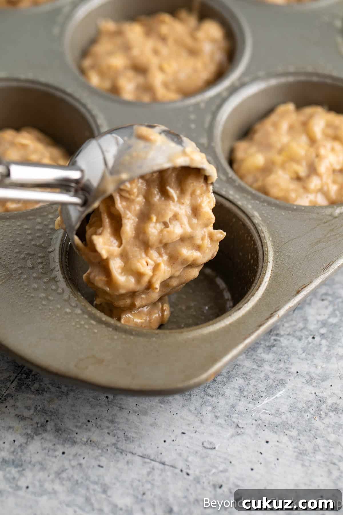 Scooping muffin batter into a muffin tin. 