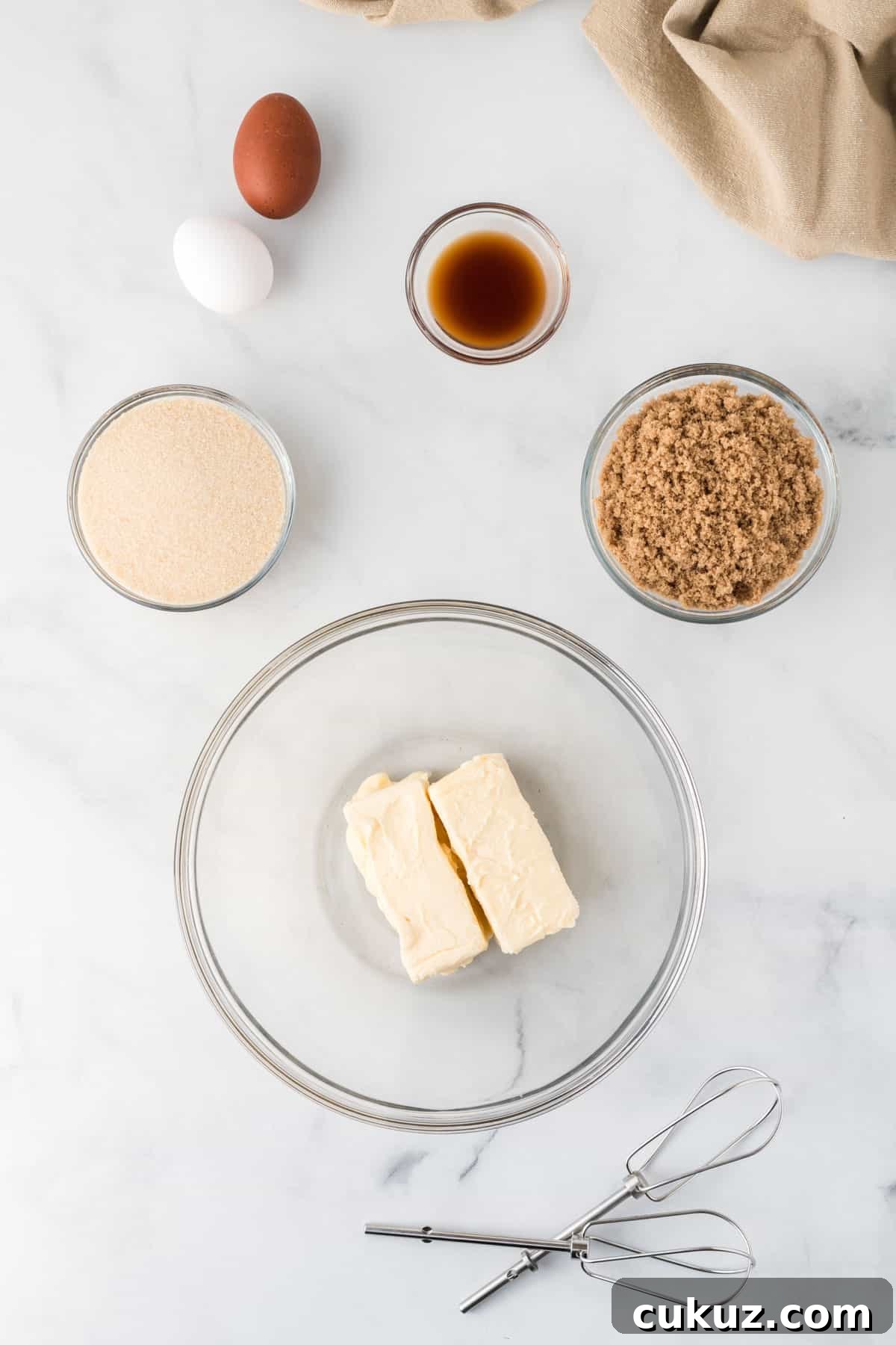 butter in a bowl surrounded by the sugar, eggs, and vanilla extract