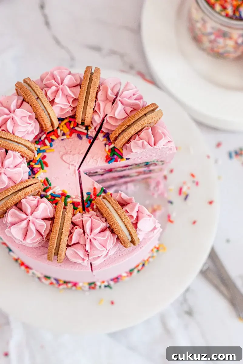 A pink funfetti cake top with bright sprinkles, pink frosting swirls, and gold oreo cookies sandwiches on the top. There is a slice taken out of the cut and two slices cut into it.