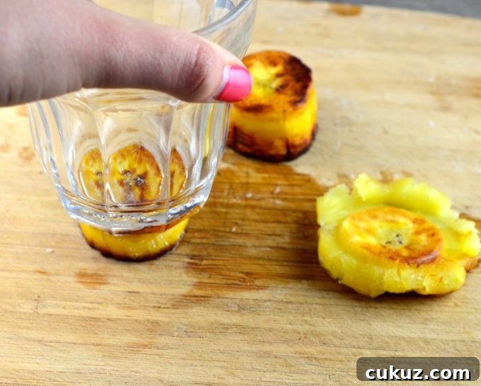 smashing a cook plantain slice with a glass