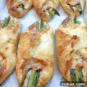6 puff pastry asparagus and ham wraps on a plate.