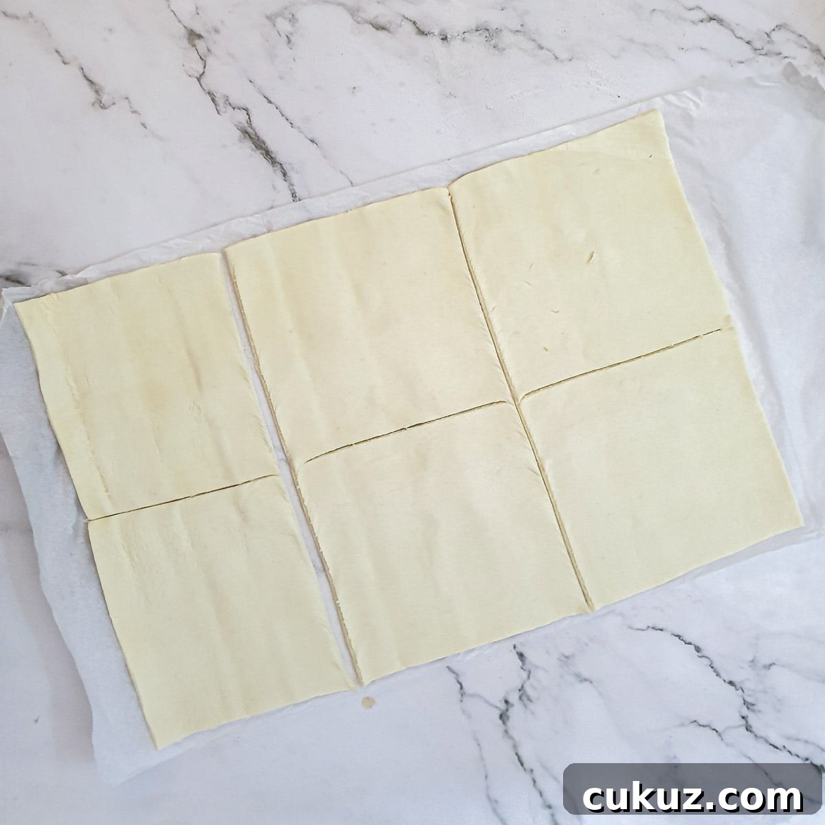 A sheet of puff pastry cut into 6 squares.