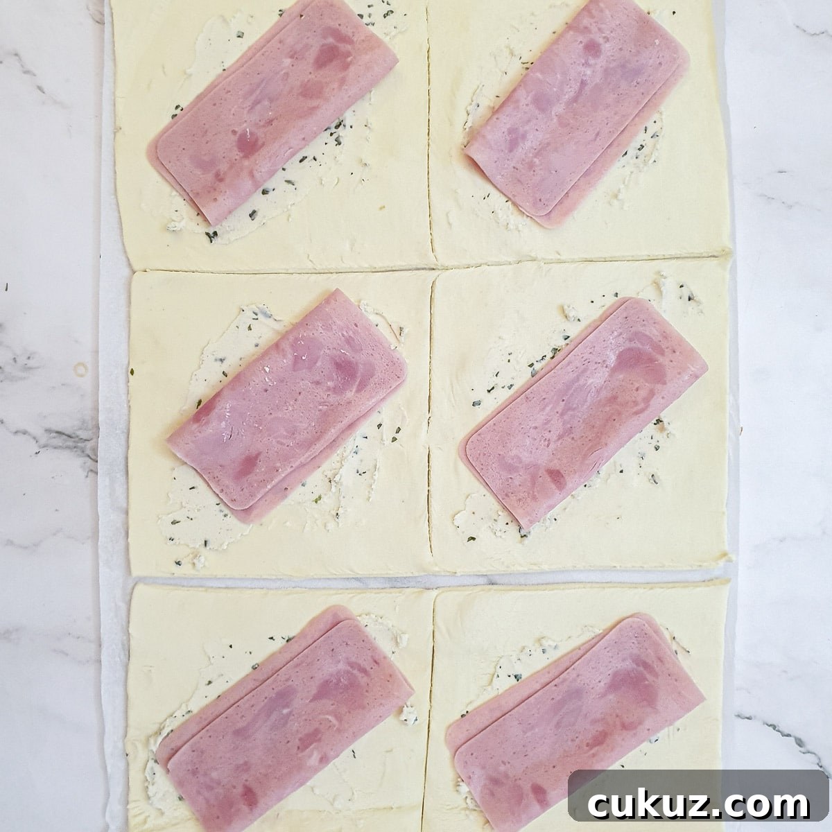 Slices of han on top of the puff pastry squares.
