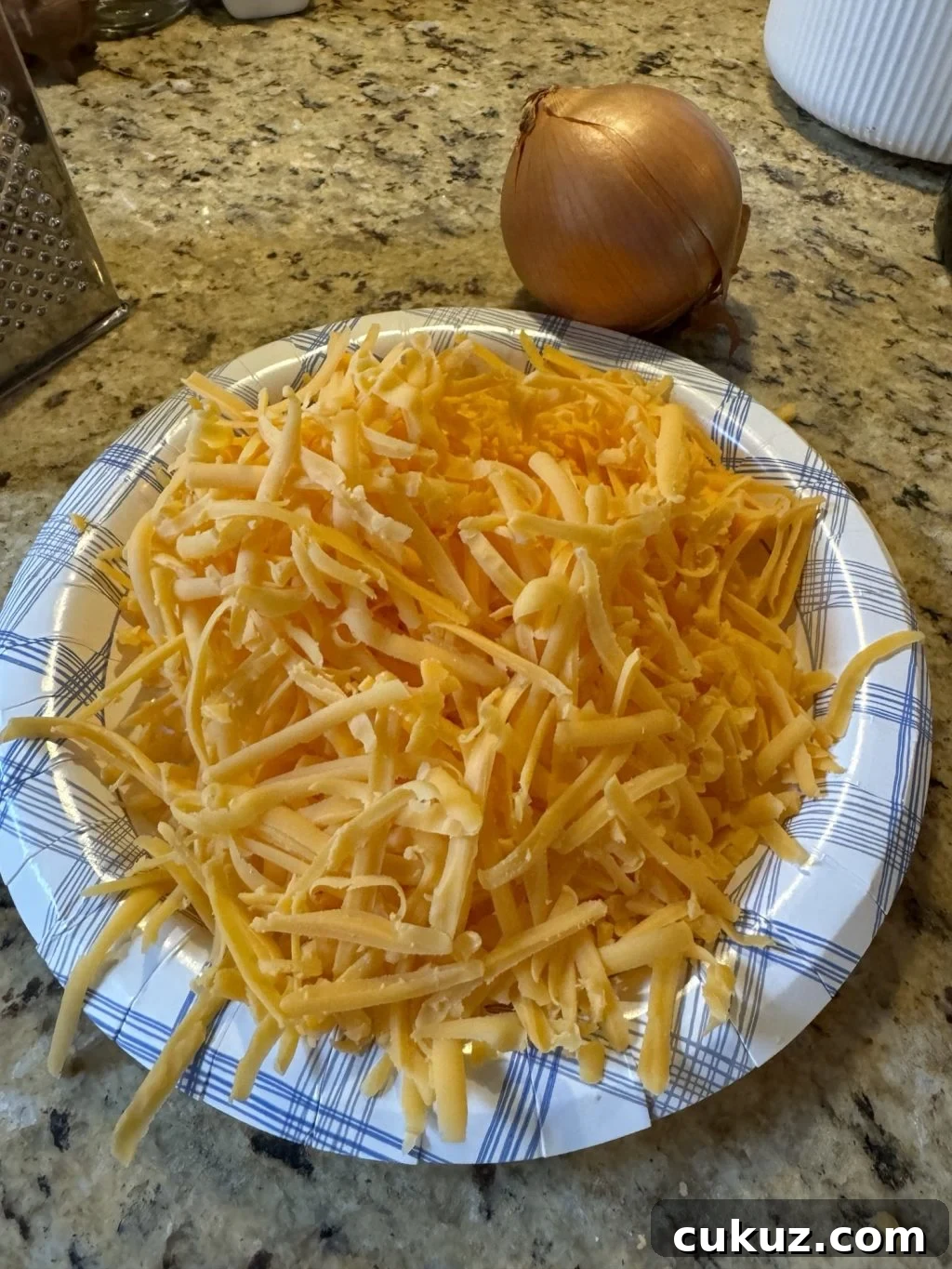 Bite-Sized Cheesy Snack Balls: Party Appetizer Recipe 3 Shredded cheese in a paper bowl next to an onion.