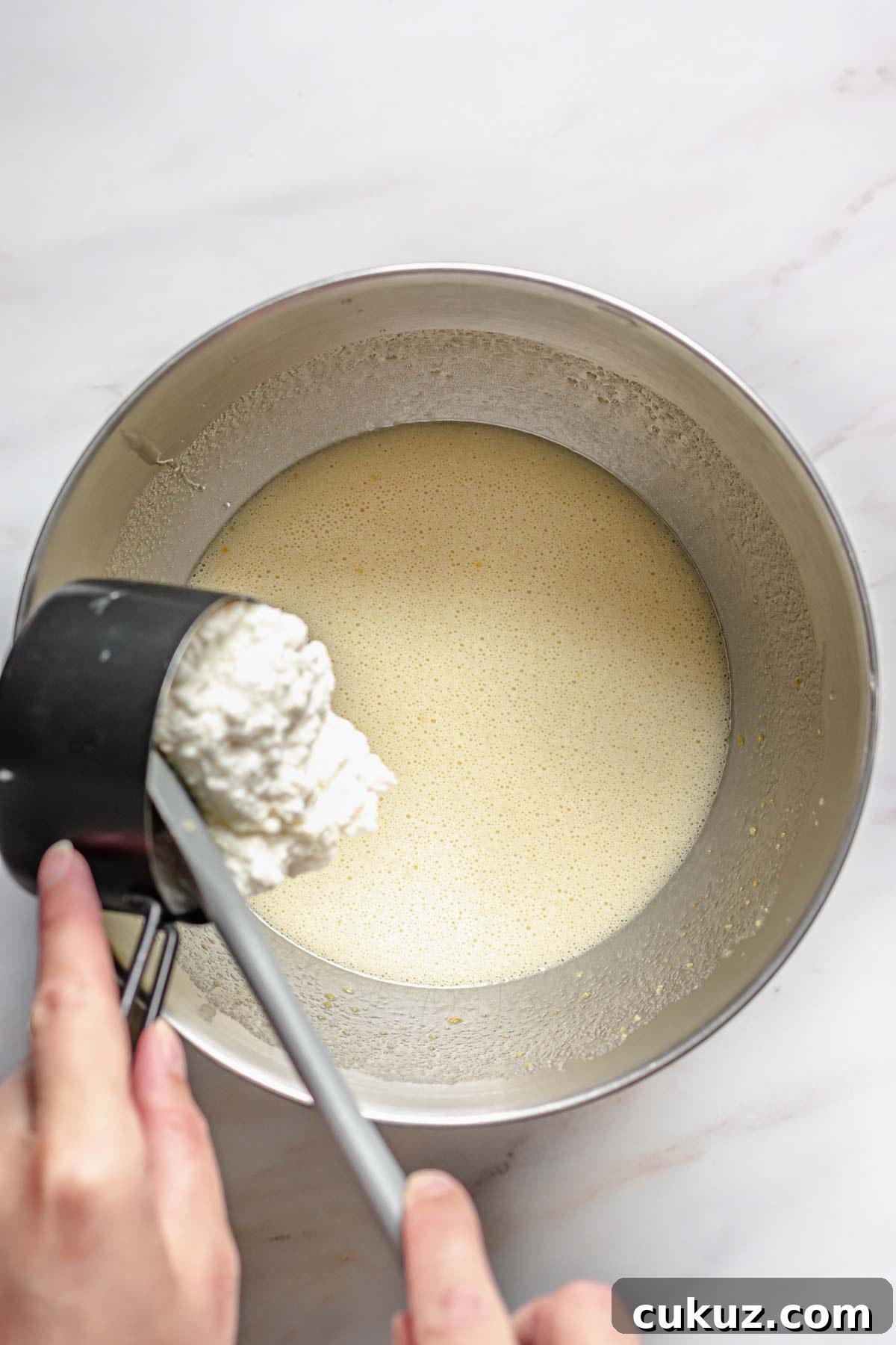 Ricotta being added to the batter.