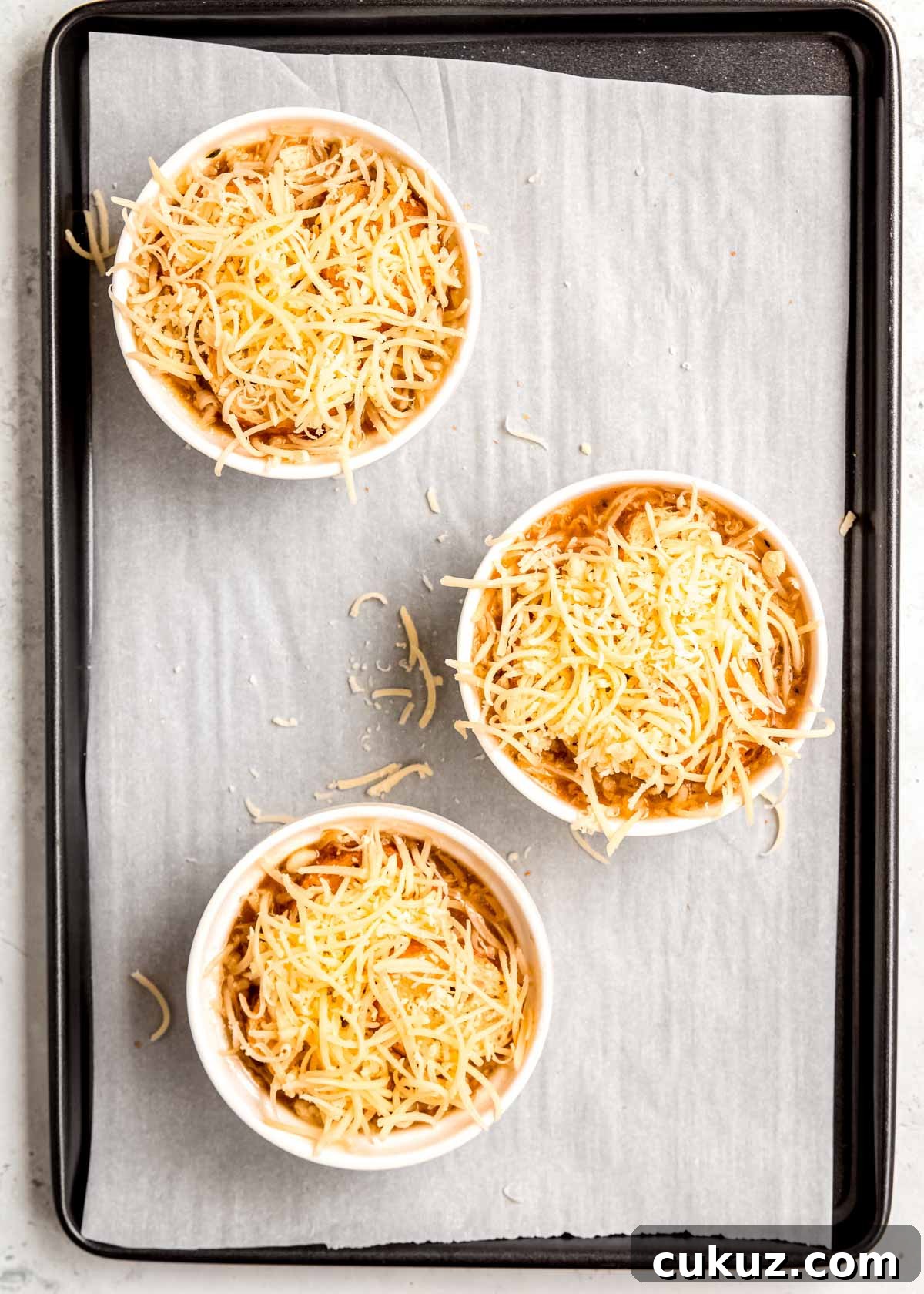 french onion chicken soup and toasted baguette slices covered with shredded gruyere cheese