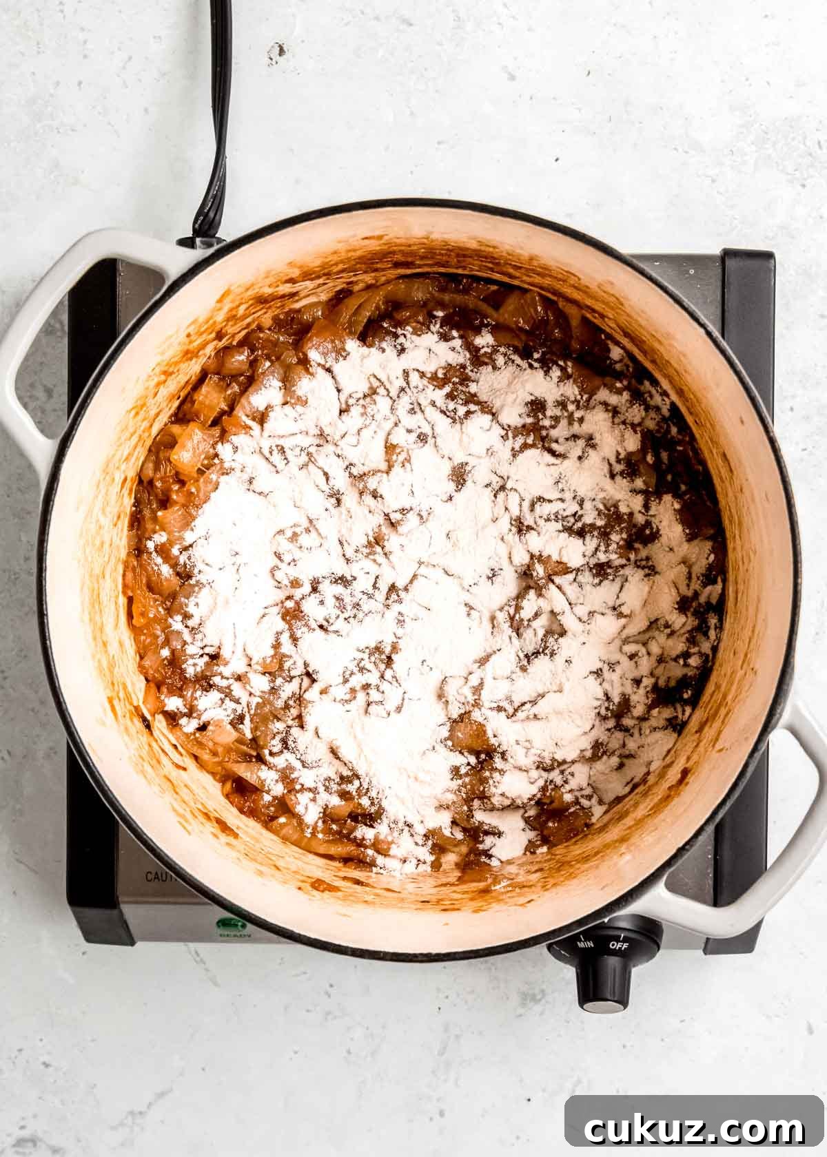flour sprinkled over caramelized onion in a dutch oven