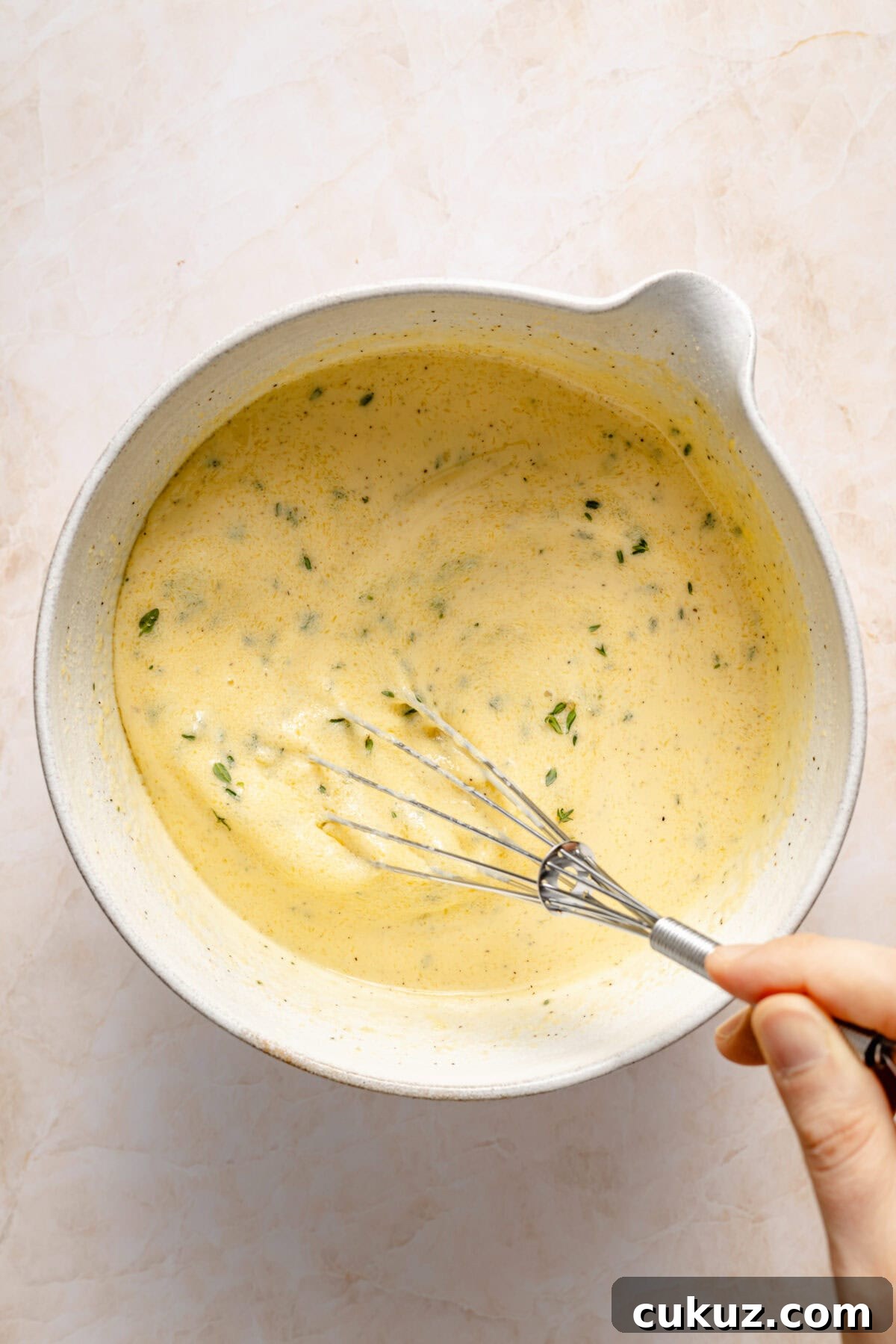 Croque Monsieur Breakfast Casserole egg mixture in bowl with whisk.